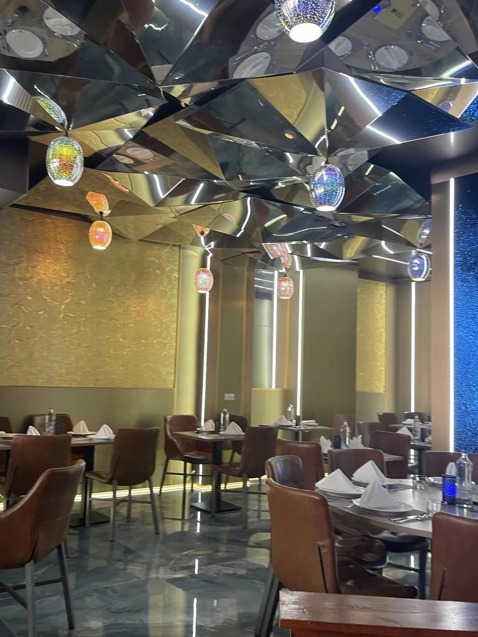 Restaurantzaal met gespiegeld plafond, gouden wanden en gedekte tafels