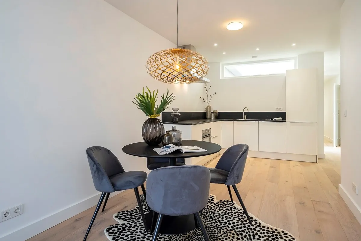 Eethoek met rotan hanglamp en witte keuken, Hellevoetsluis